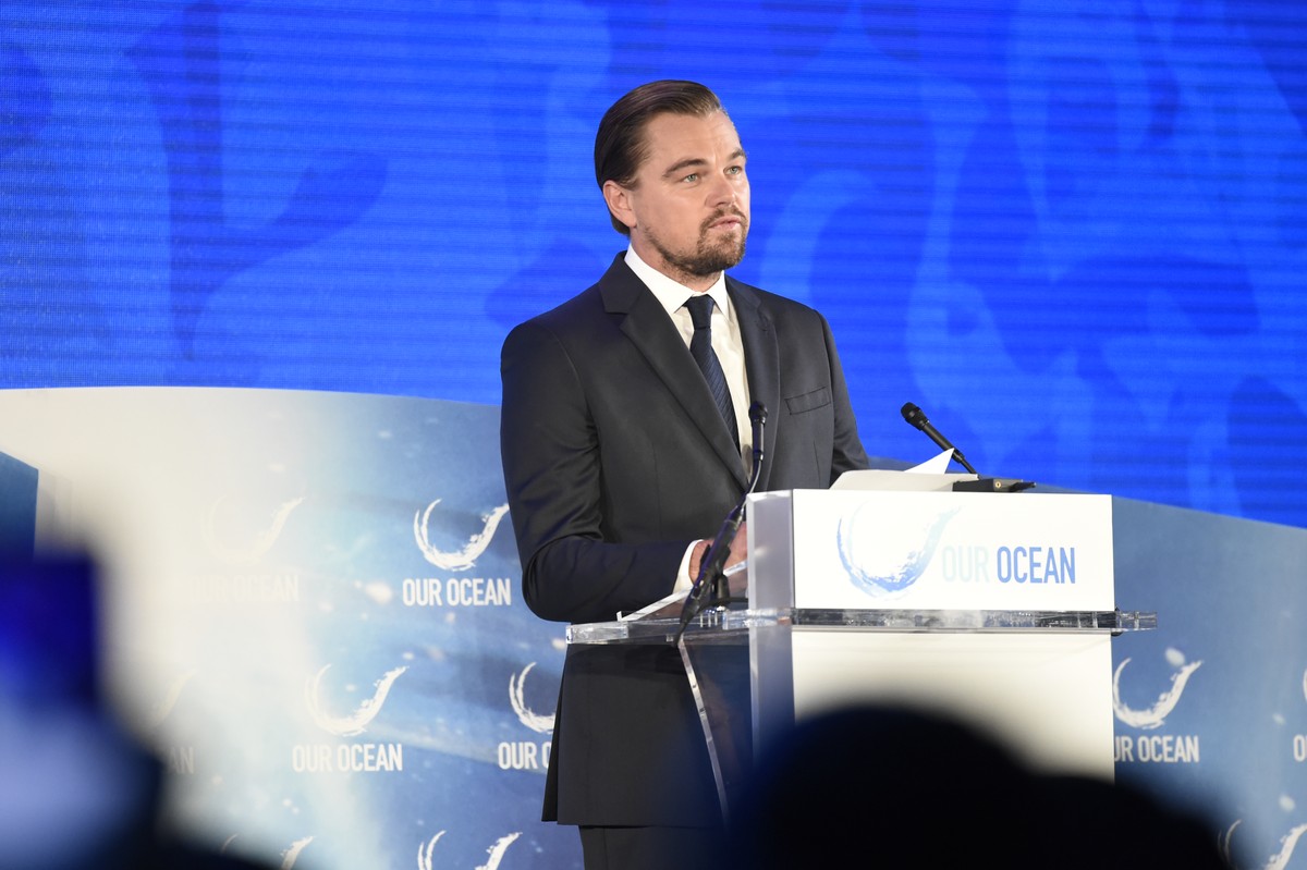 Leonardo DiCaprio stands at a lectern during a public conference.