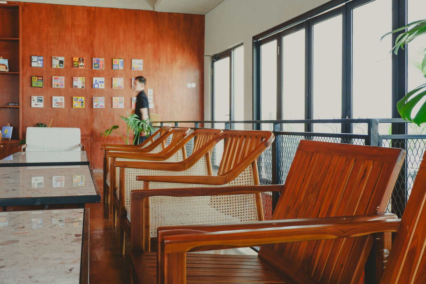 Wooden armchairs and tables line the windows of a café.