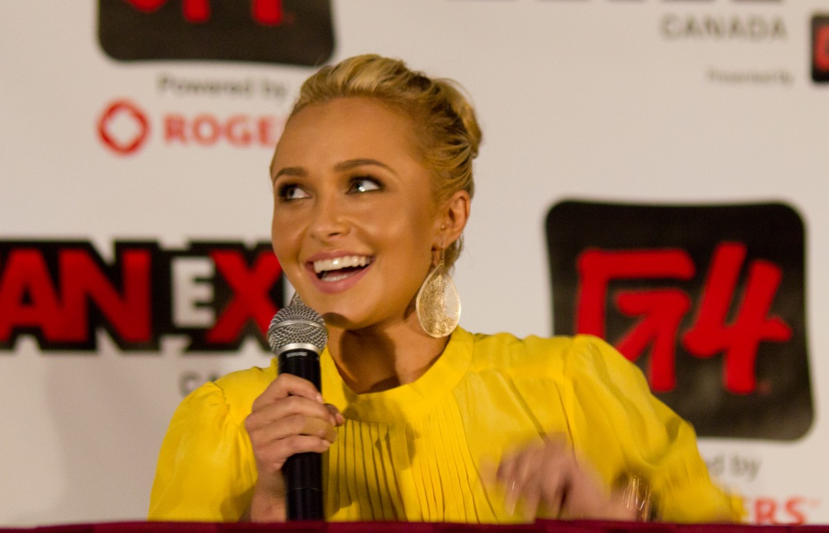 Hayden Panettiere holds a microphone in front of a Fan Expo backdrop.